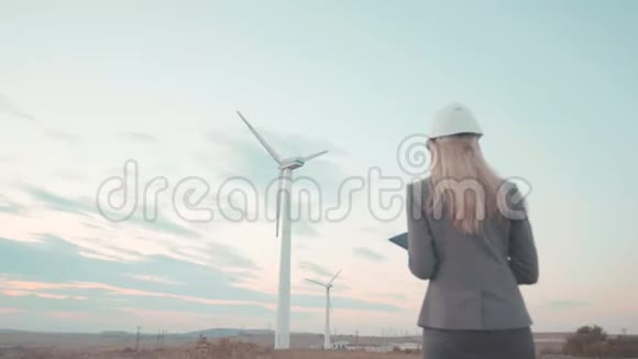 一个戴着头盔的年轻女商人正站在风车旁边青年建筑业务这就是视频的预览图