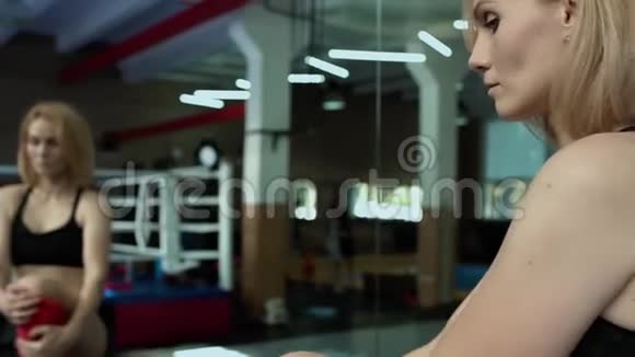 穿着运动服的美女在健身房的镜子前伸展身体视频的预览图