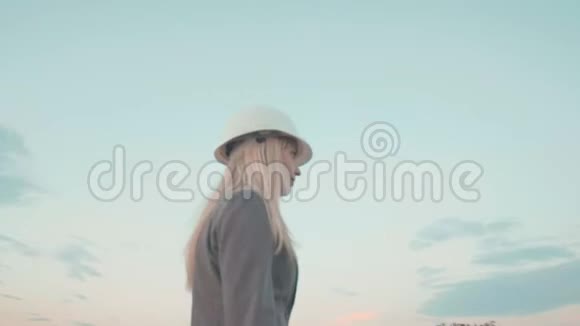 戴着头盔的年轻女商人在风车的背景上建筑界的美女视频的预览图