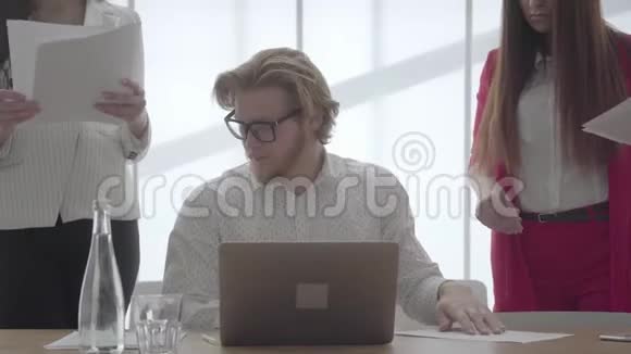 一位戴眼镜的成功金发男子坐在一间光线舒适的办公室里桌上挂着上网本视频的预览图