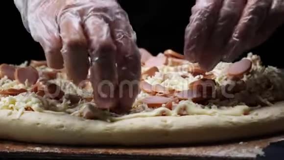 在白色硅胶手套上特写制作比萨饼并在比萨饼面团上添加切块香肠框架视频的预览图