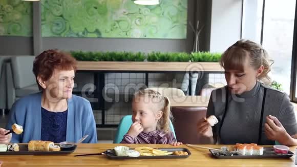 孩子从母亲和祖母手中愉快地吃东西视频的预览图