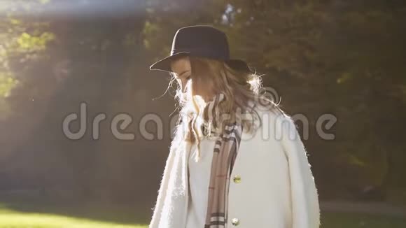 戴着帽子的时髦金发女人转向相机在公园里微笑视频的预览图