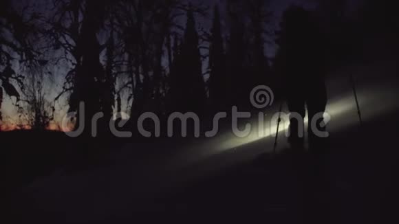 一个人拿着手电筒在雪夜森林里滑雪视频的预览图