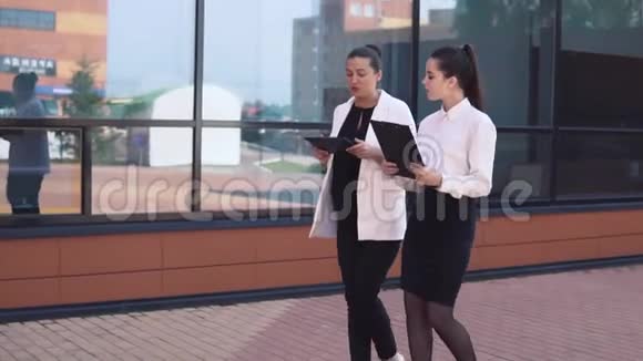 两个年轻的商业女孩走在街上讨论一个工作项目慢动作视频的预览图