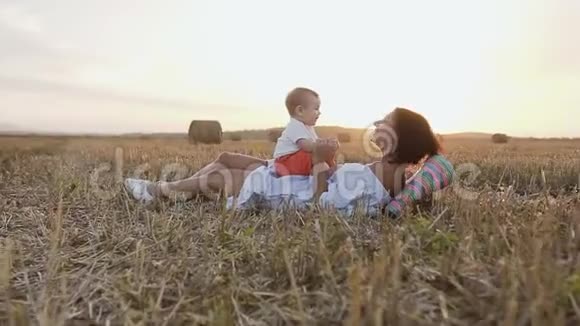 年轻的女人和她可爱的6个月的男孩在野外玩一位年轻的母亲抱着一个小儿子视频的预览图