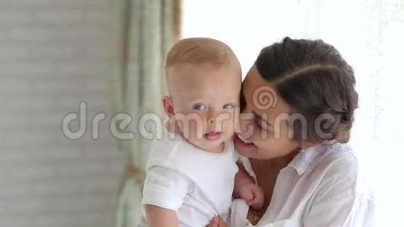 快乐的年轻妈妈在卧室的家里亲吻和拥抱她的新生儿视频的预览图