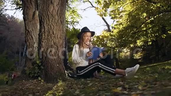 时尚的金发女人在公园里放松和看书视频的预览图
