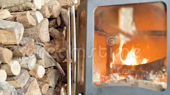 白天在一大堆耐火玻璃后面的一个自制的现代炉子里在一堆燃烧的木柴旁边特写视频的预览图
