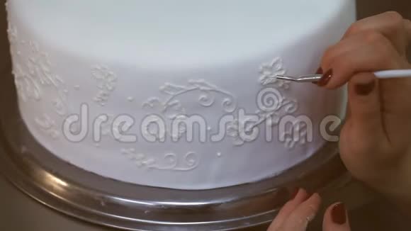 糖果师在白色结婚蛋糕上画奶油花视频的预览图