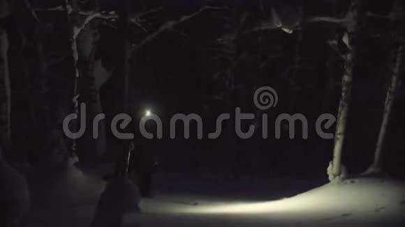 一个人拿着手电筒在雪夜森林里滑雪视频的预览图