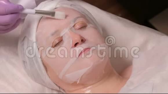 一位在美容中心参加皮肤恢复会议的女士美容师用白色的刷子涂上凝胶视频的预览图