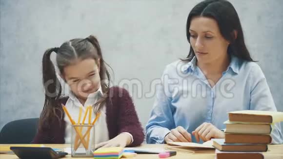 坐在桌子旁的漂亮女学生在家和她妈妈做作业视频的预览图