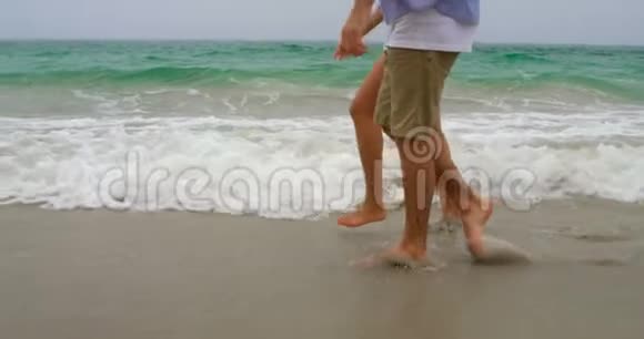 一对夫妇手牵手在海滩上散步4k视频的预览图