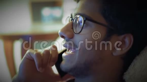 特写戴眼镜的印度男人坐在沙发上通过电话下达命令视频的预览图