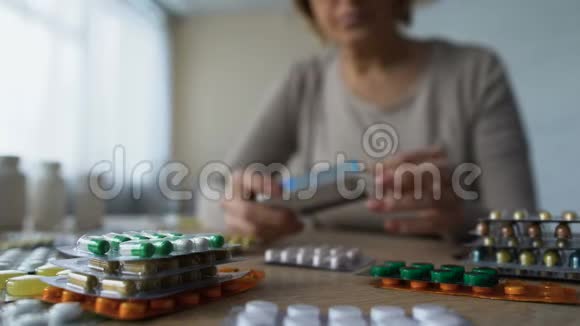 桌上药片的特写和后面吃药的老妇人消费主义视频的预览图