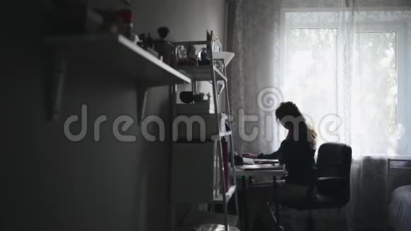 一位成功的年轻女孩坐在家里的桌子旁翻阅一些报纸的侧景画像视频的预览图