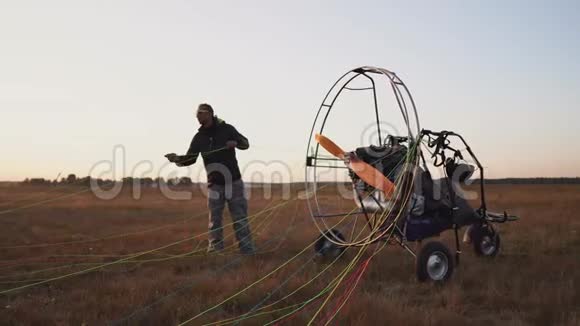 一辆汽车滑翔机的男性驾驶员将降落伞固定在滑翔机的身体上为飞行做好准备并进行检查视频的预览图