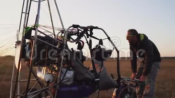 一名驾驶机动滑翔伞的男子将降落伞连接到滑翔伞的身体上准备飞行和检查视频的预览图