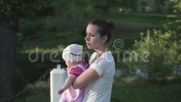 妈妈带着婴儿走着手里拿着她阳光明媚侧射视频的预览图