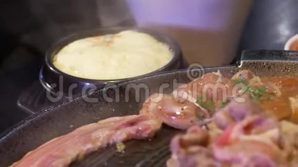 服务员在餐桌上为顾客烹煮烧烤肉的动作视频的预览图