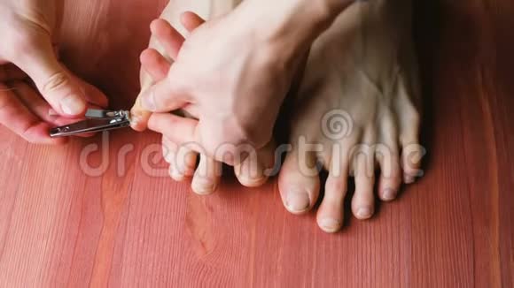 人剪脚趾甲一个男人在家中做足疗在地板上在最高的视野视频的预览图