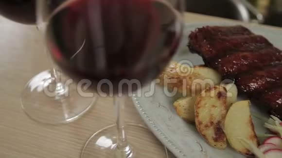 两个红酒杯烤土豆烧烤排骨和凉拌菜视频的预览图