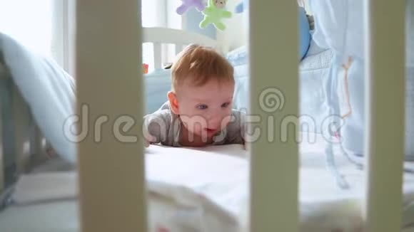 一个小孩在婴儿床上的特写镜头笑着从婴儿床的格子间侧视快乐的童年幼稚的快乐视频的预览图