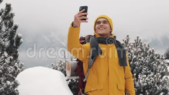 冬天美丽的山有胡子的男人穿着黄色的冬天衣服在背景下自拍视频的预览图