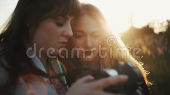 两个漂亮的女孩正在外面的数码相机上看照片近距离观察视频的预览图
