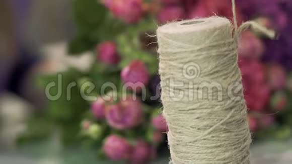 玫瑰花束背景上的缠绕绳子解开在卷筒上焦点从线轴移动视频的预览图