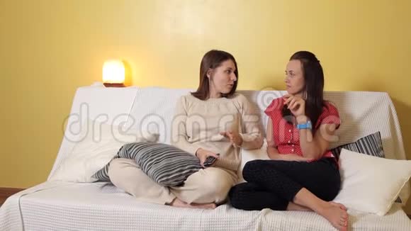 两个年轻女孩坐在家里的沙发上在雨天和交流家雨友谊视频的预览图