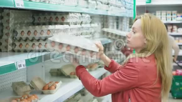超市里的一个女人走过篮子经过柜台4K特写女人选择鸡蛋在一个视频的预览图