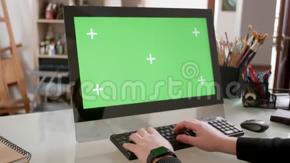 创意设计师在电脑前工作显示器上有绿色屏幕视频的预览图