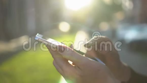 合上女人手拿白色电话智能手机金色阳光背景阳光阳光上网视频的预览图