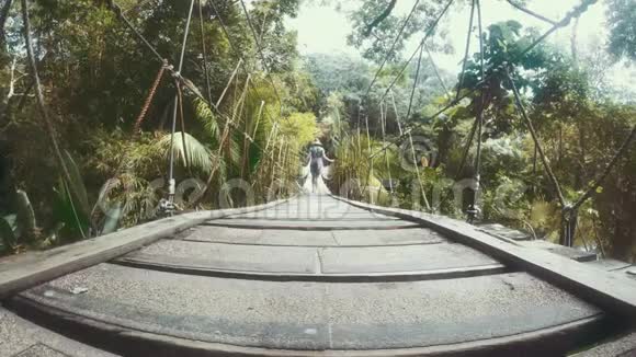 穿过丛林山谷的一座木桥的女人4K视频的预览图