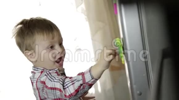 小男孩教字母表把字母放在厨房的冰箱上视频的预览图