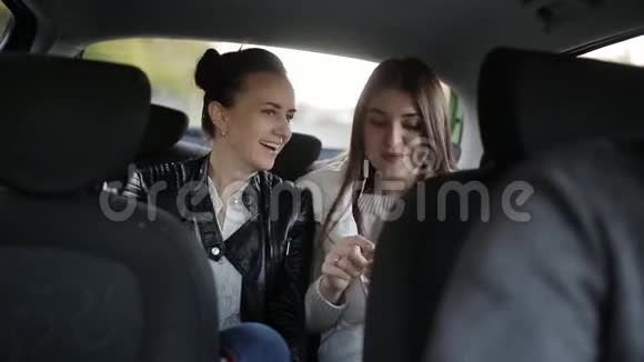 两个女孩坐出租车在后座说话和听音乐耳机视频的预览图