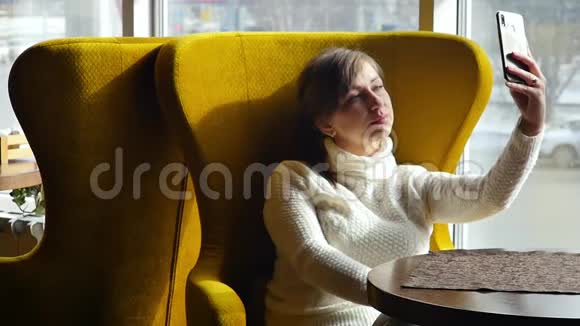 漂亮的女人坐在咖啡馆里在智能手机上自拍商务午餐慢动作视频的预览图