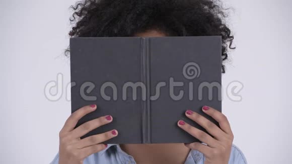 带眼镜的非洲年轻女子的脸用书遮住脸视频的预览图