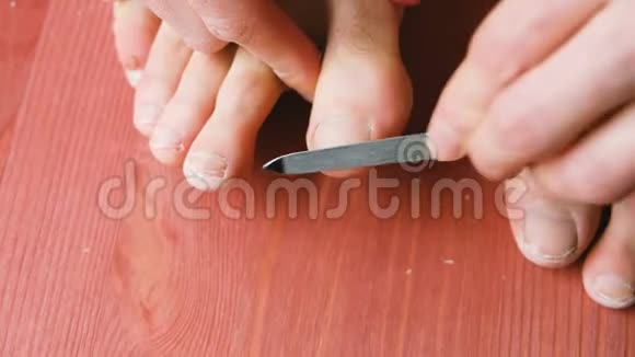 男人正在用指甲锉特写锯他的拇指指甲一个人在家里地板上修脚视频的预览图