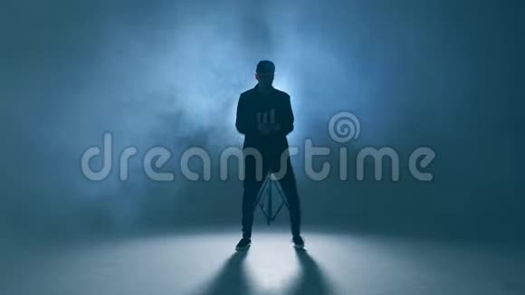 时髦的现代风格嘻哈舞者在蓝色工作室背景下展示他的舞蹈视频的预览图