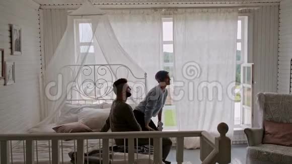 一对年轻漂亮的夫妇穿着温暖的毛衣在一间乡间房子靠窗拥抱和家庭关系视频的预览图