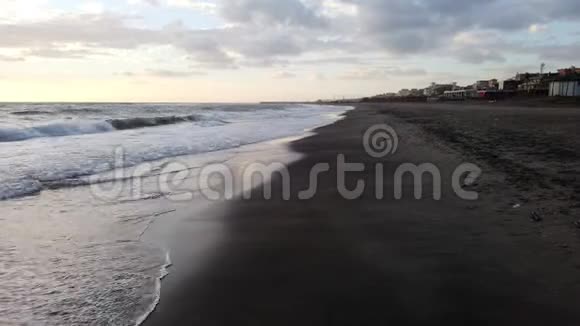 在阴天的时候在靠近海岸的沙滩上散步视频的预览图