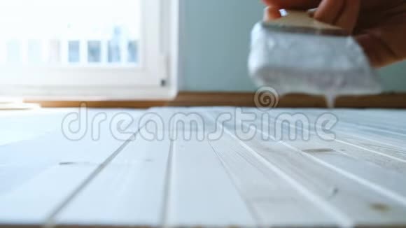 女孩用白色油漆缓慢地画一个木制地板选择性聚焦特写视频的预览图