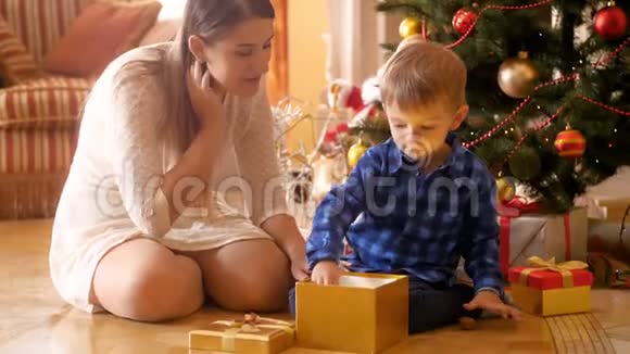 4k段快乐欢笑的小男孩坐在圣诞树下从礼盒里拿出玩具视频的预览图