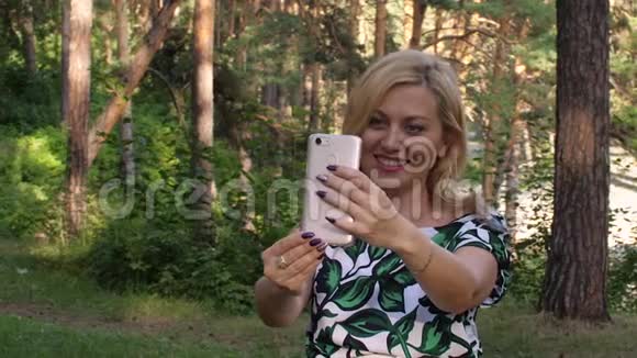 快乐的女人在夏天公园用手机打视频电话视频的预览图