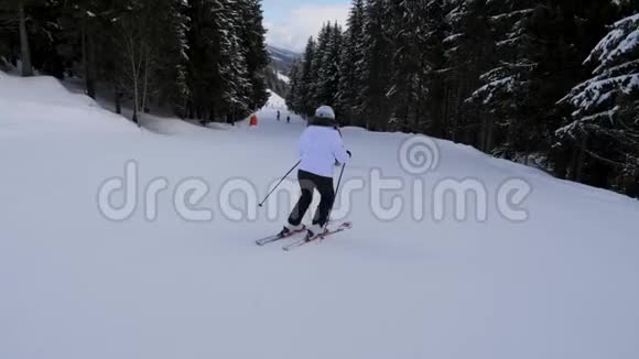两名运动女滑雪运动员在山下的森林山坡上滑雪视频的预览图