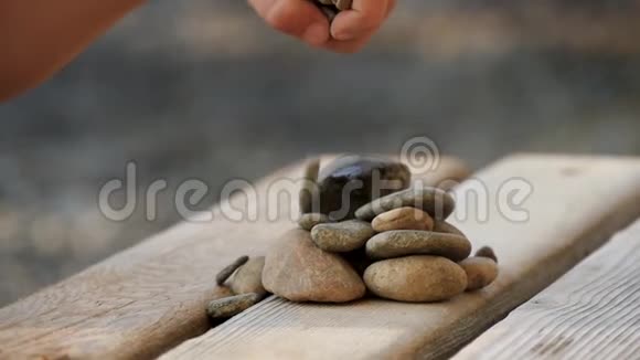 一个小孩在海边的木摊上玩石头动作缓慢特写镜头视频的预览图