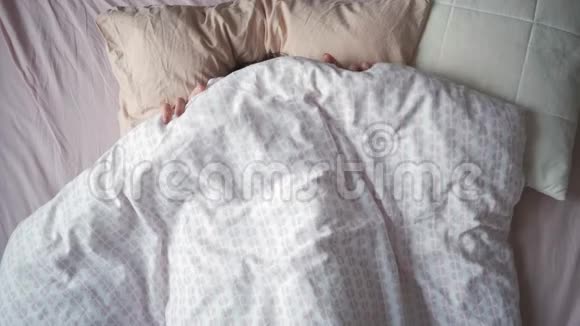 一位年轻迷人的女士早晨躺在床上伸伸手的俯视图视频的预览图